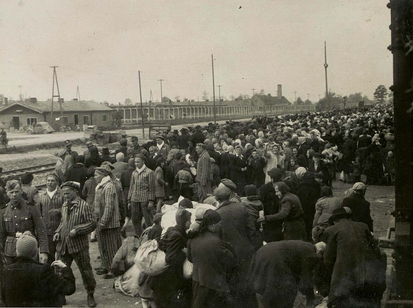 Late May 1944: Hungarian Jews are emerging from the cattle cars on the Birkenau ramp. The prisoners in the striped uniforms are members of the cleaning commando (called “Kanadakommando” in camp slang.) While they were risking capital punishment by telling deportees what awaited them, they clandestinely convinced thousands of Hungarian children to claim to be older than they actually were. (Photo: Hungarian National Museum/Yad Vashem)